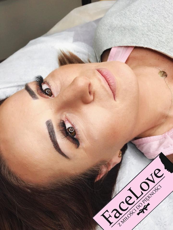 Kobieta leżąca na leżance z przedłużonymi rzęsami i świeżo wyregulowanymi brwiami, widoczny logo salonu kosmetycznego w rogu.