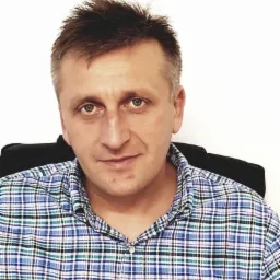 Portret mężczyzny w koszuli w kratę z logo Polo Ralph Lauren, o krótkich ciemnych włosach i niebieskich oczach, na jasnym tle.