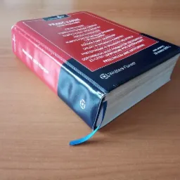 Książka 'Prawo Karne. Zbiór przepisów' z niebieską zakładką, leżąca na drewnianym biurku, widoczna z góry pod kątem.