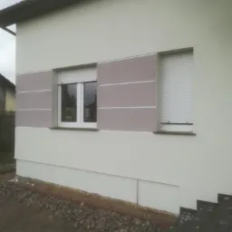 Wykończona elewacja domu w Połczynie-Zdroju z oknami z roletami zewnętrznymi i dekoracyjnymi panelami w odcieniach beżu i brązu.