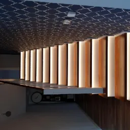 Nowoczesna aranżacja wnętrza z drewnianą ścianą akcentującą, podświetloną pionowymi pasami LED, widok z dołu na wzorzysty sufit.