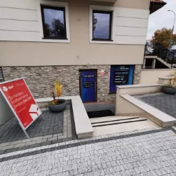 Fasada budynku z szyldem serwisu komputerowego widoczna nad wejściem, obok reklama DPD Pickup.