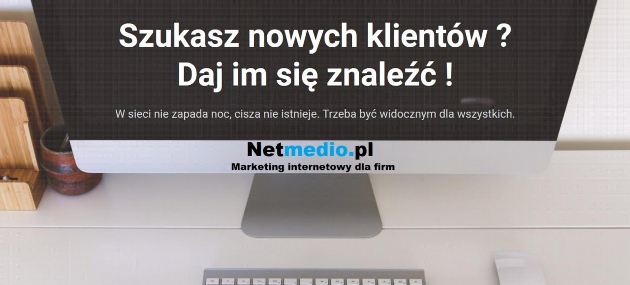 Ekran monitora iMac wyświetlający tekst 'Szukasz nowych klientów? Daj im się znaleźć!' oraz logo Netmedio.pl 'Marketing internetowy dla firm', na biurku z klawiaturą i drewnianym organizerem.