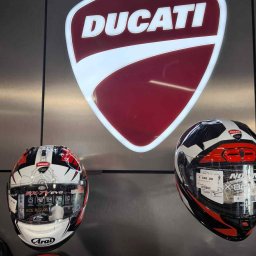 Grupa Reklamowa Prosignum Sp. z o.o - Podświetlany kaseton z logo Ducati na metalowej ścianie, poniżej kaski motocyklowe. Ekspozycja marki w salonie.