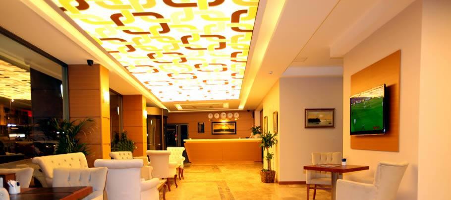 Lobby hotelowe z recepcją, białymi fotelami, telewizorem na ścianie i dekoracyjnym sufitem z motywem łańcucha.