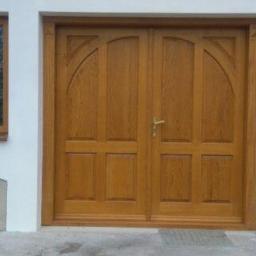 Usługi Stolarskie Marcin Biesiadecki - Dwuskrzydłowe, drewniane drzwi wejściowe w odcieniach brązu, z zaokrąglonymi górnymi panelami, flankowane symetrycznie umieszczonymi, wąskimi oknami z drewnianymi ramami, osadzone w białej, grubej...