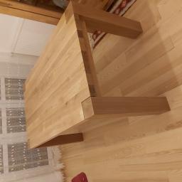 Usługi Stolarskie Marcin Biesiadecki - Solidny, jasny stół z drewna, widoczny z góry na tle drewnianej podłogi i okna z wzorzystą firanką.