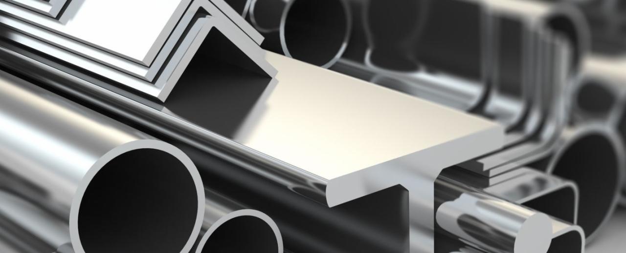 Błyszczące, metalowe rury o okrągłym przekroju oraz profile o przekroju kwadratowym i kątowniki ułożone w stos, z efektem głębi ostrości.