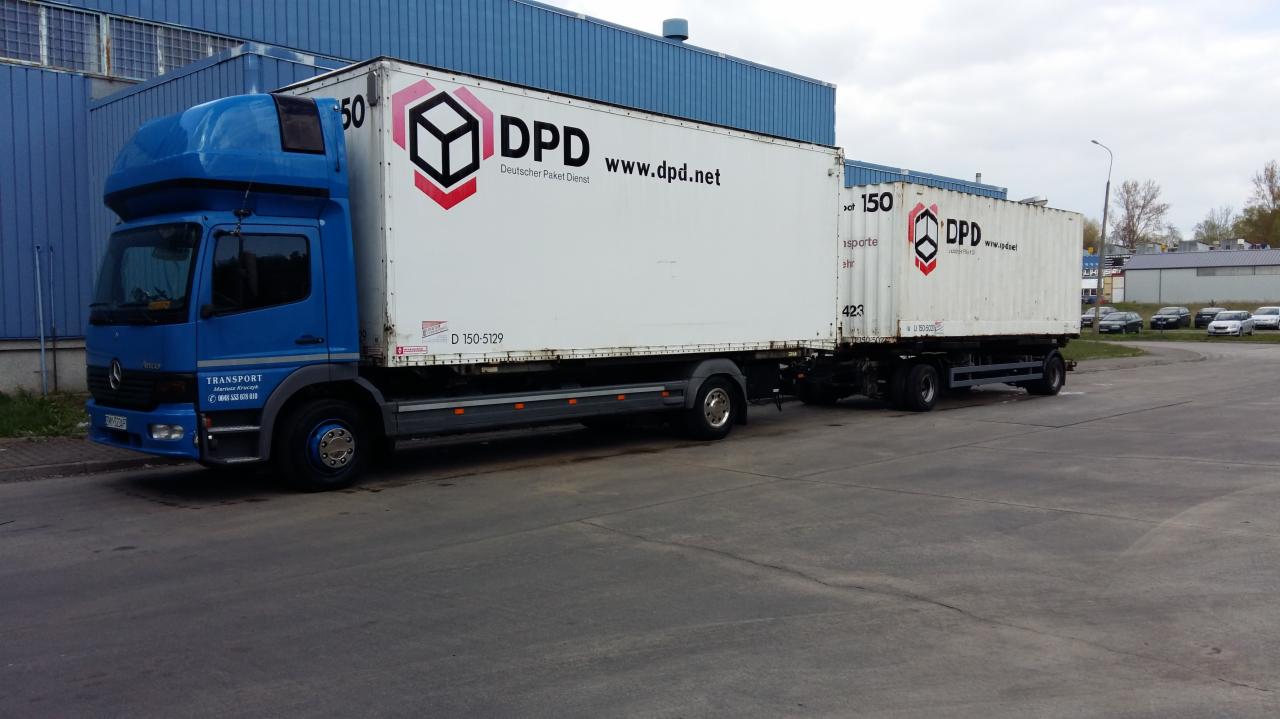 Niebieski ciągnik siodłowy Mercedes-Benz z białą naczepą DPD na betonowym placu, widoczne numery rejestracyjne i logo firmy kurierskiej, w tle budynek z blachy falistej.