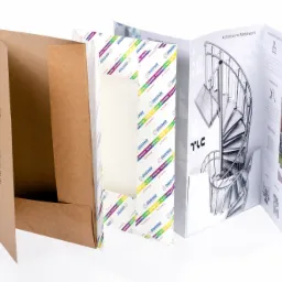 Otwarta teczka z brązowego papieru obok rozłożonej, wielostronicowej broszury reklamowej prezentującej schody spiralne i inne metalowe konstrukcje architektoniczne, na białym tle.
