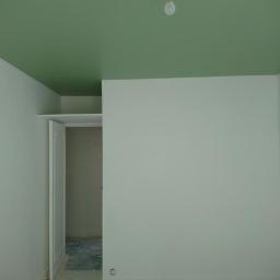 M-4 concept - Pokój w trakcie odświeżania: zielony sufit, białe ściany, widoczne zabezpieczenia podłogi, otwarte drzwi do garderoby i puszka farby przy ścianie.