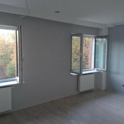 M-4 concept - Pokój po świeżym malowaniu ścian na szaro, z dwoma oknami otwartymi na jesienny krajobraz i nową podłogą laminowaną.