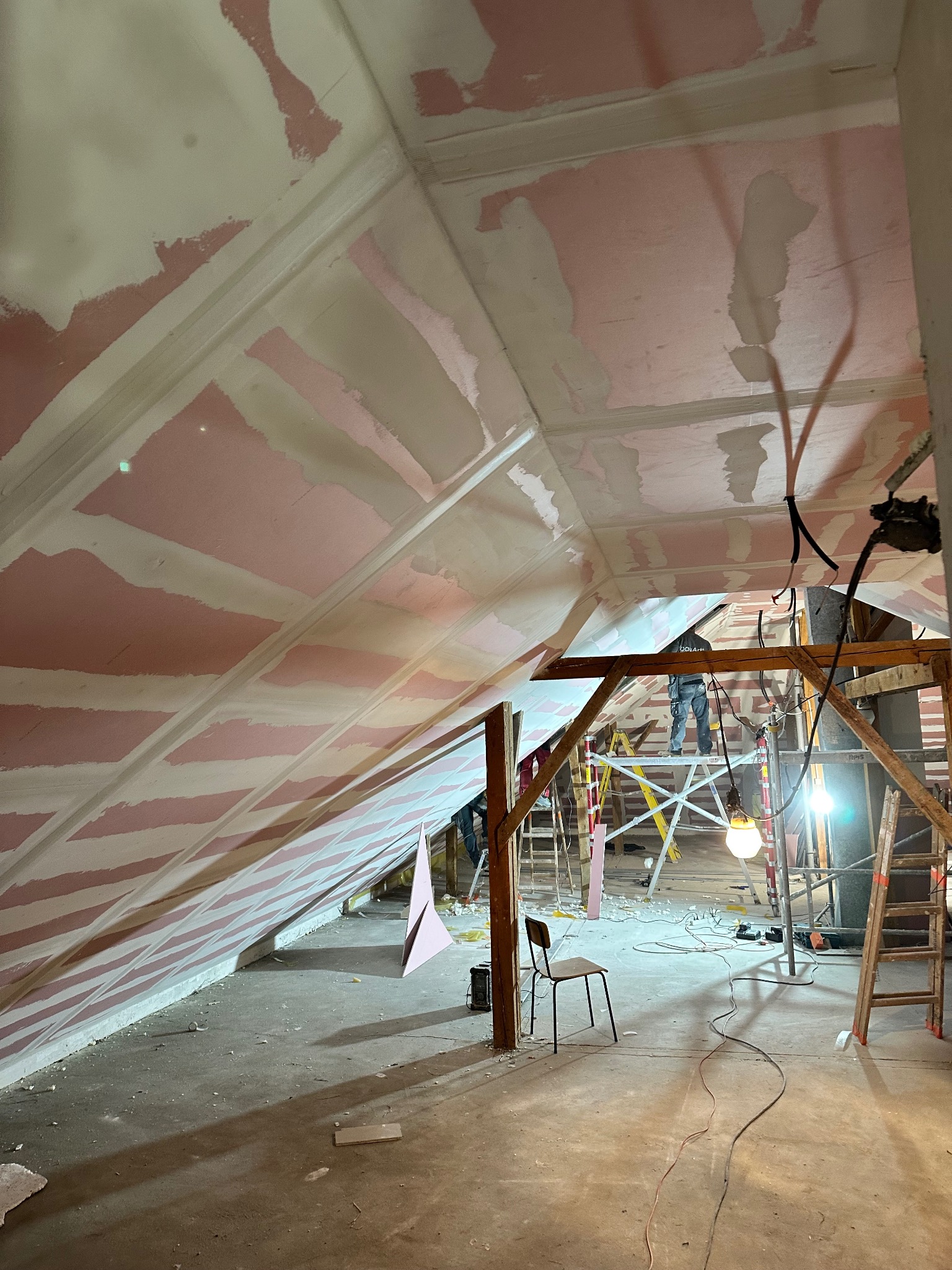 Poddasze w trakcie prac wykończeniowych: płyty karton-gips na skosach, częściowo zaszpachlowane, widoczne rusztowania i narzędzia. Prace na wysokości.
