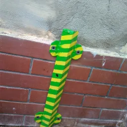 Uziemienie pionowe, pomalowane w zielono-żółte pasy, przymocowane do ściany z cegły i surowego tynku. Widoczne śruby mocujące.