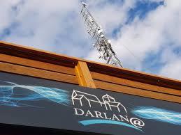 Metalowa wieża telekomunikacyjna widoczna z dołu, zza krawędzi budynku z logo firmy Darlan@