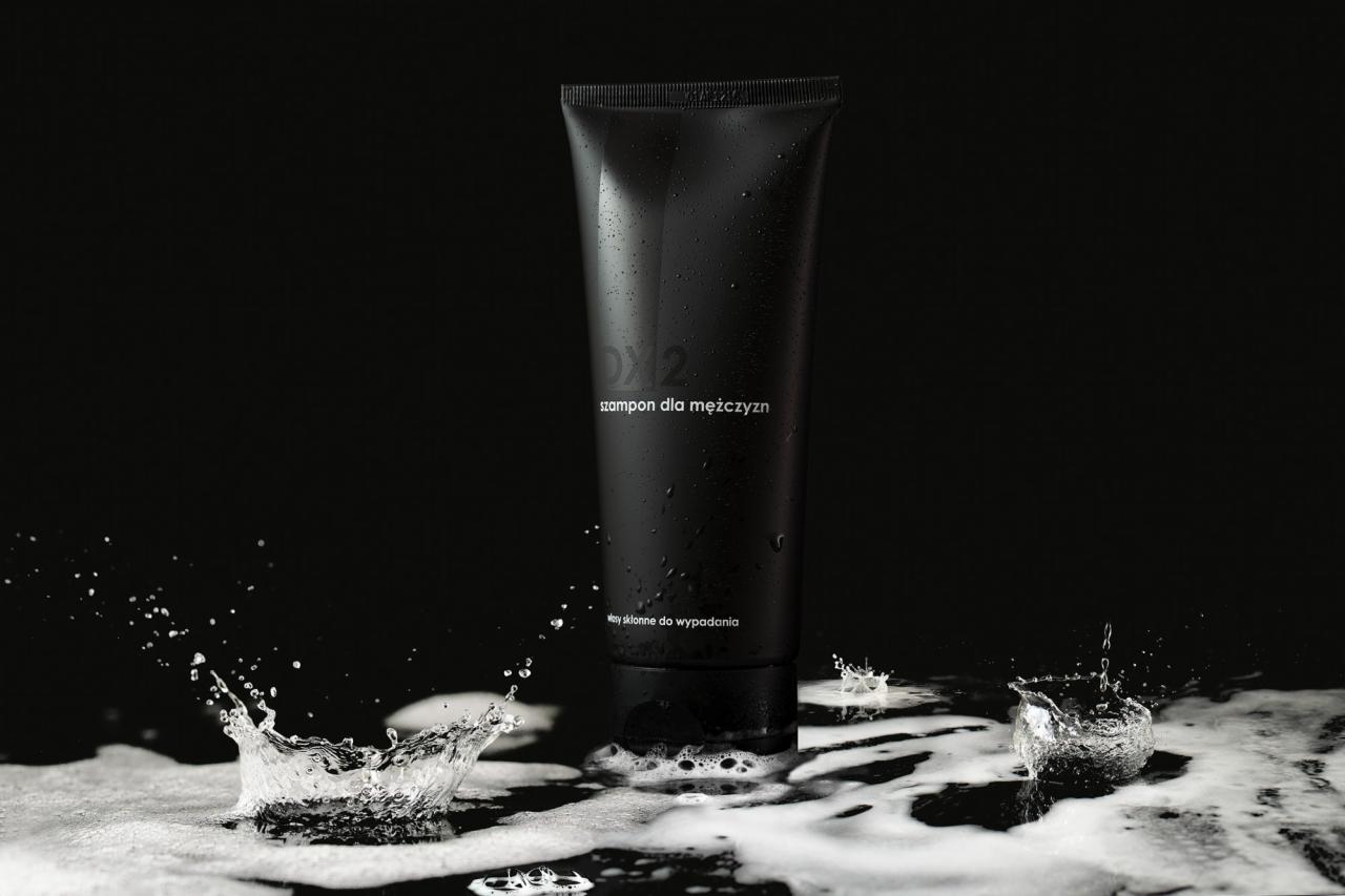 Czarna tuba szamponu DX2 dla mężczyzn na błyszczącym podłożu z pianą i kroplami wody w dynamicznym ruchu.