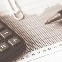 Kalkulator, długopis i spinacz na wydruku z danymi liczbowymi. Monochromatyczne ujęcie z bliska.