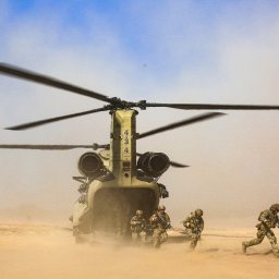 Photography by Denis Rubelt - Śmigłowiec transportowy Chinook na pustyni, z którego wysiadają żołnierze w pełnym rynsztunku, unoszący się piasek.