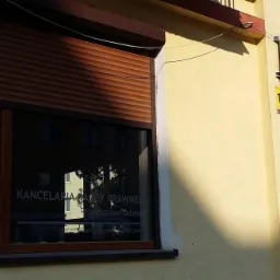 Zewnętrzny widok budynku z szyldem informującym o Kancelarii, rolety częściowo zasłonięte, widoczny numer budynku 10 oraz logo KIRP na oknie.