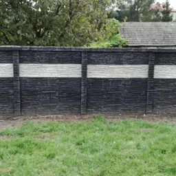 Nowoczesne, dwukolorowe ogrodzenie betonowe z poziomymi pasami, widok z zewnątrz na tle zielonej trawy i drzew.