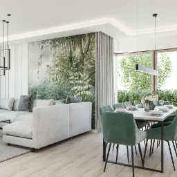 Nowoczesny salon z narożną sofą, stolikiem kawowym, stołem jadalnym z zielonymi krzesłami i fototapetą z motywem roślinnym, oświetlony wiszącymi lampami.