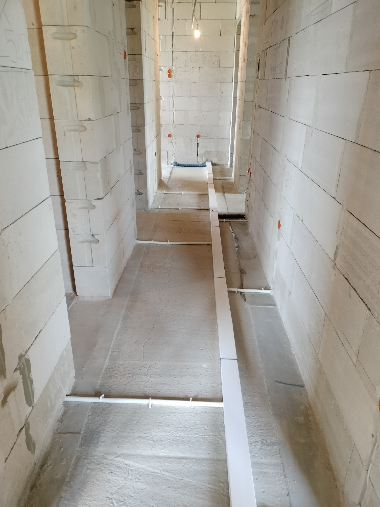 Wnętrze w trakcie prac elektrycznych: widoczne kable i rury instalacyjne na ścianach z betonu komórkowego, surowy stan, przygotowanie do dalszych prac wykończeniowych.