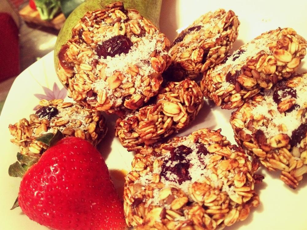 Owsiane ciasteczka z suszoną żurawiną i wiórkami kokosowymi na talerzu, obok świeża truskawka i gruszka.