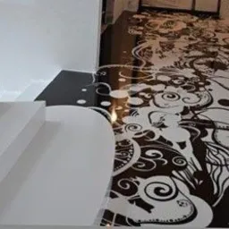 Czarno-biała posadzka z żywicy epoksydowej z abstrakcyjnym, dekoracyjnym wzorem przypominającym roślinne ornamenty, schody w tle.