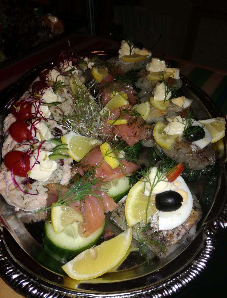 Srebrna patera z różnorodnymi kanapeczkami, dekorowanymi łososiem, ogórkiem, jajkiem, cytryną, majonezem i kiełkami, podana podczas cateringu.