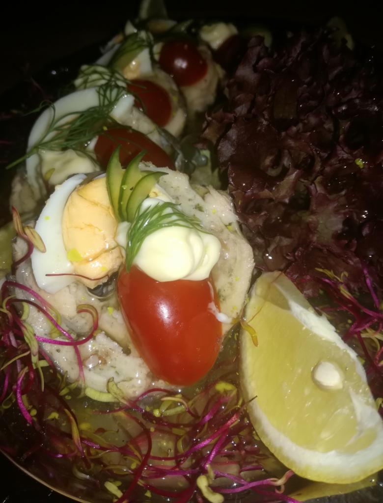 Apetyczna sałatka z jajkiem, pomidorkami cherry, cytryną i sosem, przygotowana przez firmę z Poznania. Dekoracja z kopru i sałaty.