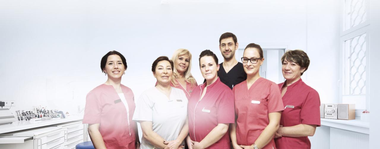 Zespół medyczny w strojach roboczych pozuje w jasnym, sterylnym gabinecie z widocznym sprzętem medycznym w tle.