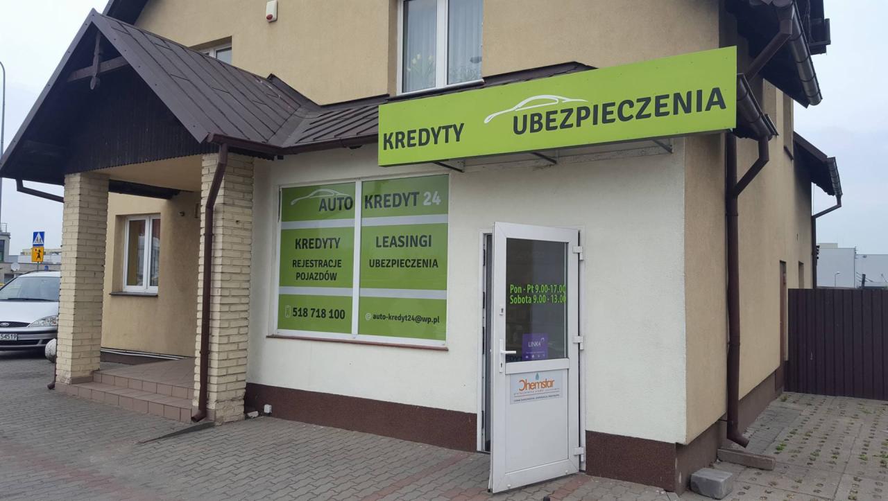Fasada budynku z szyldem 'Kredyty Ubezpieczenia' i plakatem 'Auto Kredyt 24' z informacjami o kredytach, leasingu i rejestracji pojazdów.