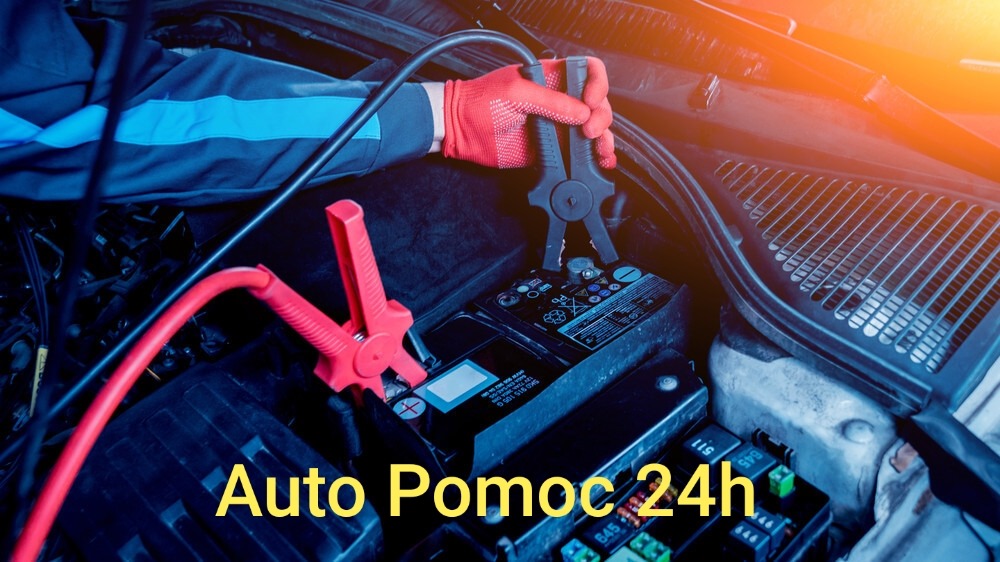 Rozruch silnika samochodowego za pomocą kabli rozruchowych; czerwone kable podłączone do akumulatora, ręka w czerwonej rękawicy trzyma czarny zacisk.