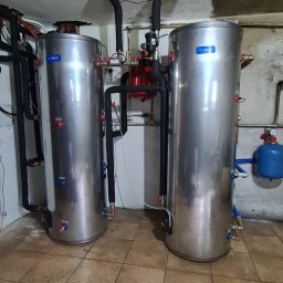 HEGAM - Dwa zbiorniki buforowe Proheat z instalacją hydrauliczną w kotłowni w Kamienicy. Widoczne rury w izolacji, zawory i manometry. Podłoga wyłożona płytkami.