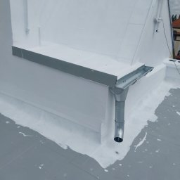 PHU FENIKS Robert Zmitrowicz - Biały, płaski dach po renowacji w Gdańsku, z widoczną metalową rynną i obróbkami blacharskimi. Świeżo nałożona warstwa hydroizolacji. Detal dachu po remoncie.