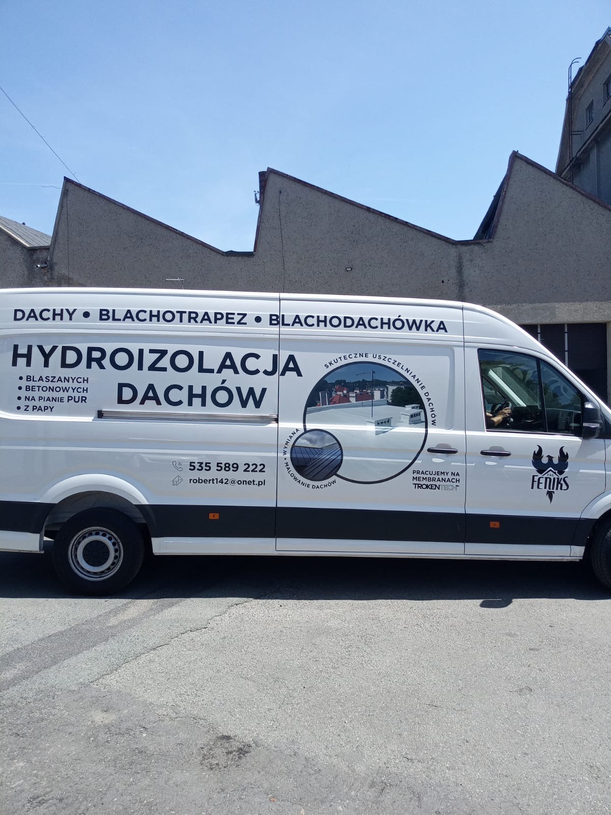 Biały samochód dostawczy z reklamą firmy dekarskiej: hydroizolacja dachów, blachodachówka, blacha trapezowa i dachy. Widoczny numer telefonu i adres e-mail.