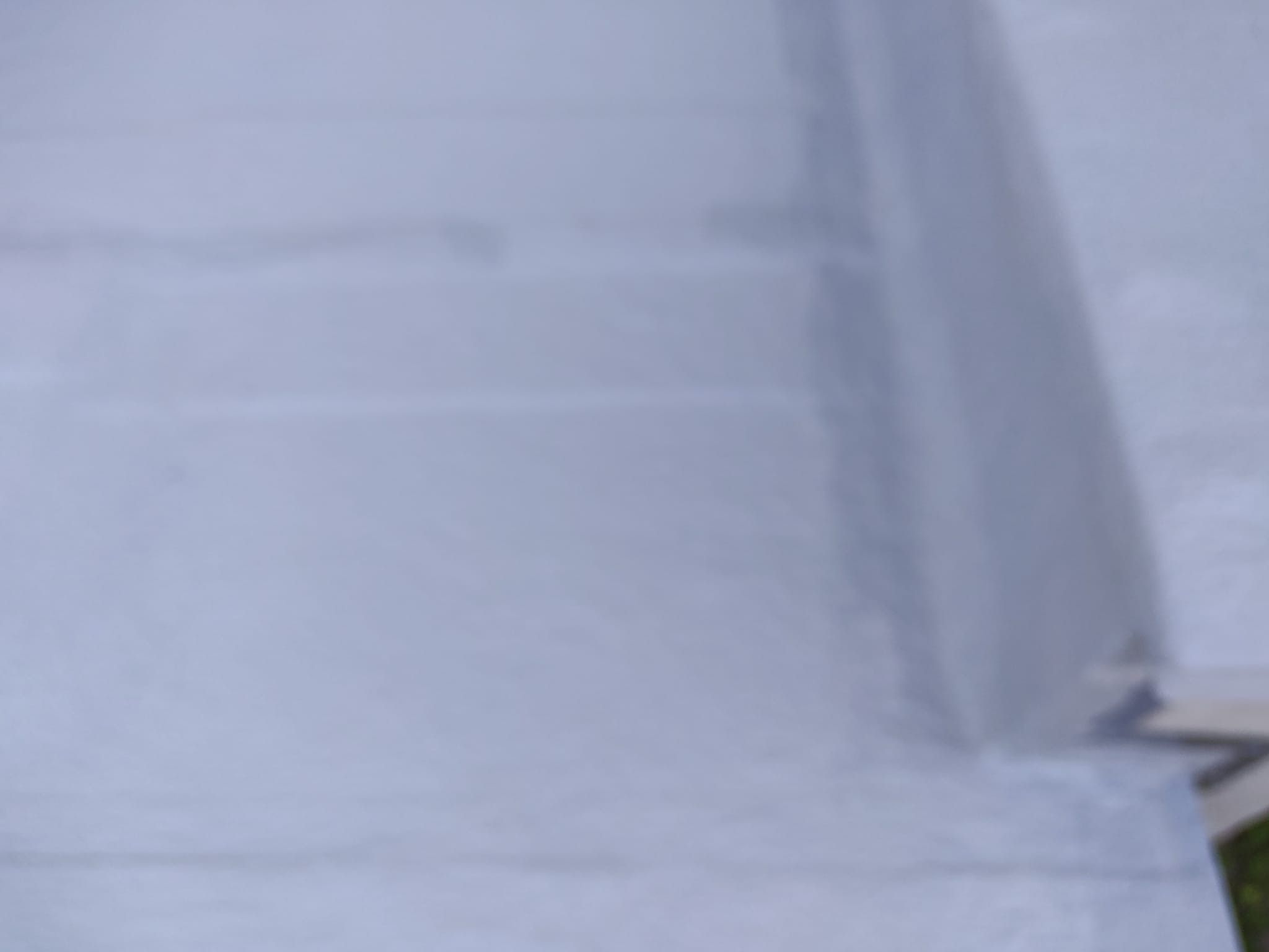 Szary dach z widocznym fragmentem obróbki blacharskiej przy krawędzi. Ujęcie z bliska, ukazujące detale łączeń i fakturę materiału.