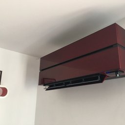 Klima Solution - Bordowy klimatyzator ścienny w nowoczesnym wnętrzu, obok półka z ramką ze zdjęciem śpiącego dziecka.