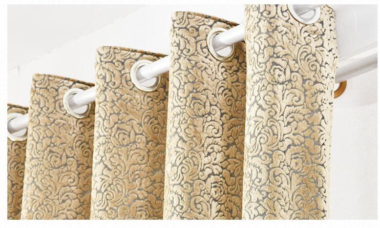 Beżowe, wzorzyste zasłony z przelotkami na białym karniszu, widoczne z bliska w dziennym świetle.