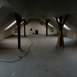 RO-STA Firma Ogólnobudowlana Starosta Roman - Poddasze w trakcie prac wykończeniowych; widoczne okna dachowe, drewniane słupy podtrzymujące konstrukcję dachu, ściany przygotowane pod malowanie lub tapetowanie, widoczna szpachla na ścianach...