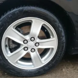 Błyszczące, mokre koło samochodu marki Toyota z aluminiową felgą o pięciu ramionach i oponą zimową z widocznym bieżnikiem.