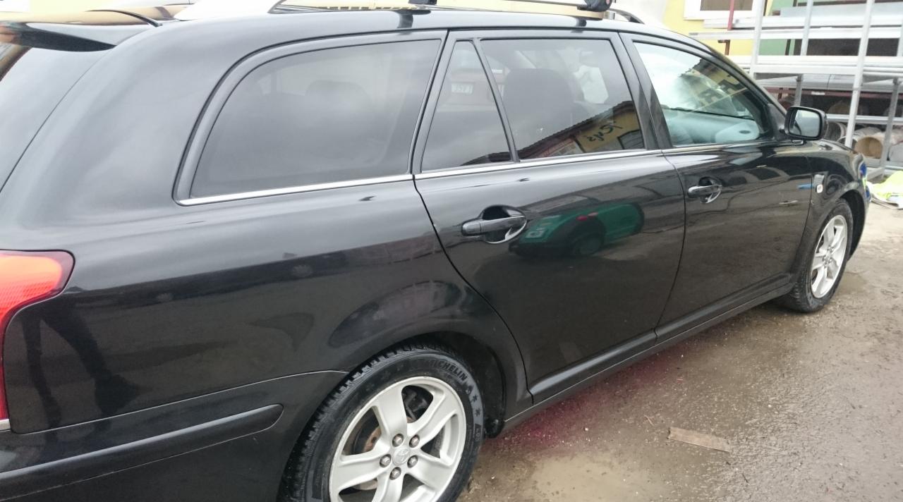 Błyszczący, czarny samochód kombi po umyciu, widoczne krople wody na karoserii i oponach, aluminiowe felgi, dach z relingami.