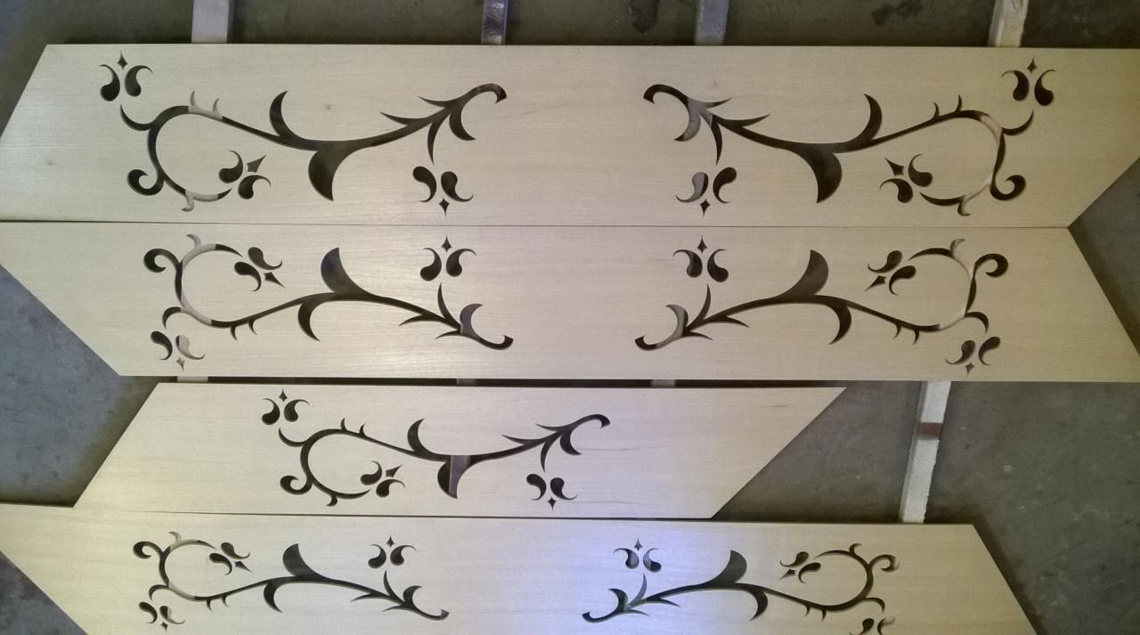 Cztery drewniane parapety z wyciętymi dekoracyjnymi wzorami roślinnymi, ułożone jeden na drugim, z widoczną strukturą drewna.