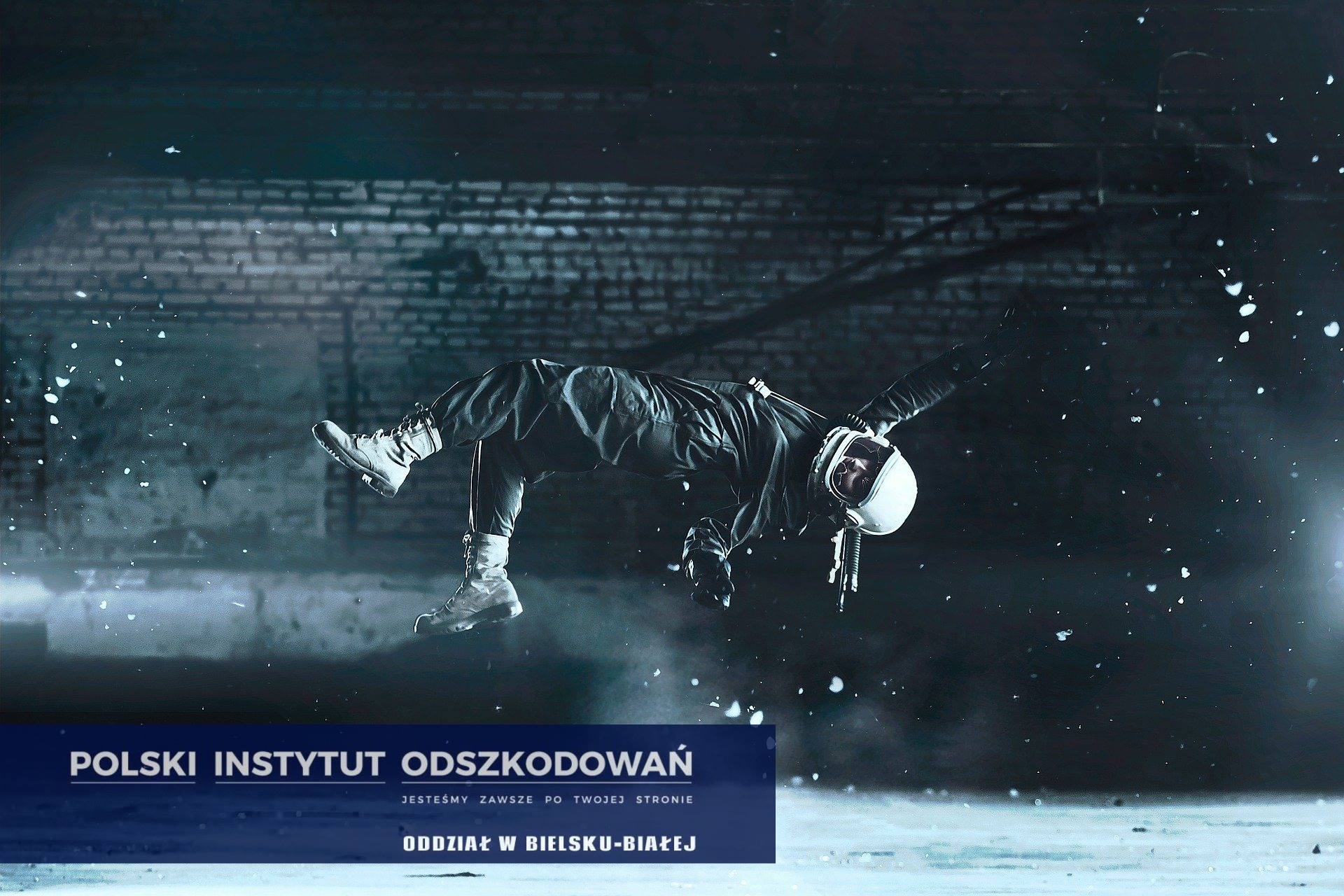 Stylizowane zdjęcie osoby w kombinezonie astronauty unoszącej się w powietrzu na tle ceglanej ściany z logotypem firmy odszkodowawczej w dolnej części kadru.