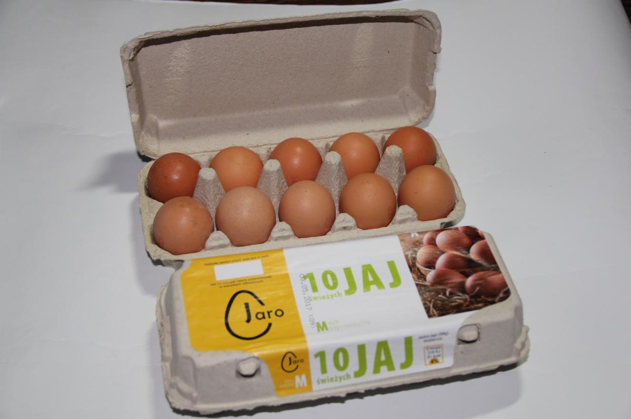 Otwarty karton z dziesięcioma brązowymi produktami spożywczymi, leżący obok zamkniętego kartonu z etykietą producenta.