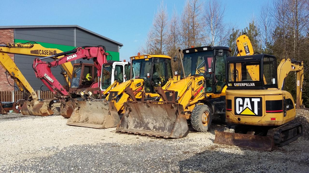 Rząd maszyn budowlanych: żółty Case, czerwony Atlas, dwie żółte koparko-ładowarki JCB 3CX i żółty mini-koparka Caterpillar CAT, stojące na żwirowym placu przed budynkiem z zielonym akcentem.