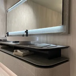 Nowoczesna łazienka z dwoma okrągłymi umywalkami nablatowymi, dużym podświetlanym lustrem i szarą szafką z oświetleniem LED u dołu.