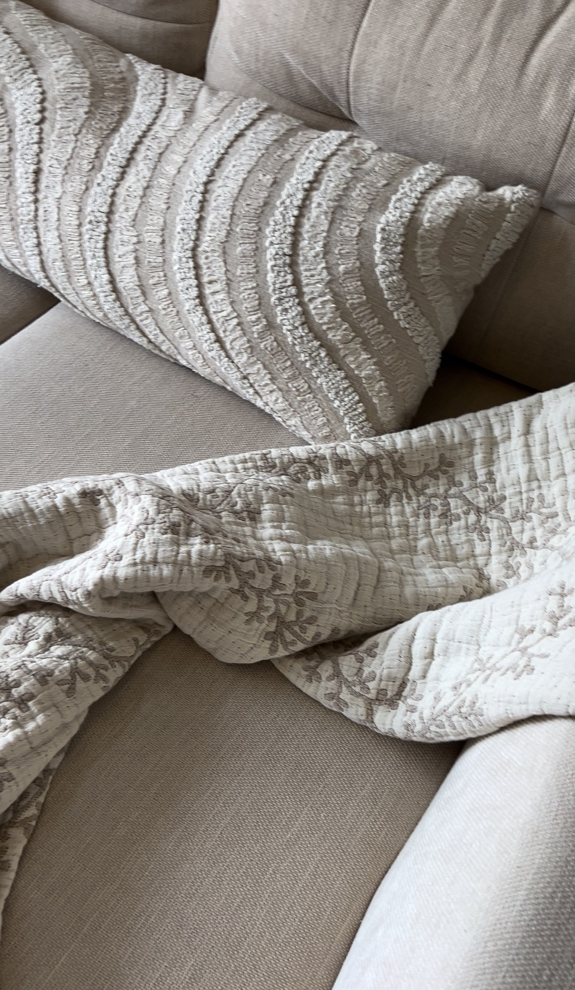 Tekstylia na sofie w odcieniach beżu: dekoracyjna poduszka z tłoczonym wzorem i pikowana narzuta z motywem kwiatowym, Toruń.