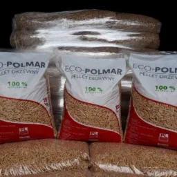 Pellet drzewny Eco-Polmar w workach 15 kg, ułożonych w stosy. Widoczne logo i napis '100% naturalny'. Całość zapakowana w folię. Prezentacja produktu.