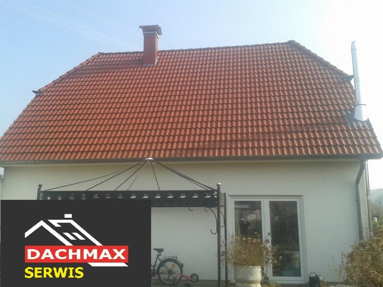 Dom jednorodzinny z czerwoną dachówką, widoczny komin i rynna, na pierwszym planie logo firmy DACHMAX SERWIS.